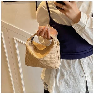 Close-up of beige woven straw handbag featuring fine texture and metal zipper detail