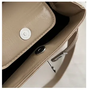 Macro view of silver magnetic snap closure on textured litchi leather bag interior
