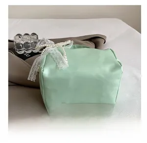 Detail showing mint green leather bag with lace bow and elegant pearl ornaments