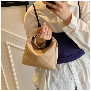 Detail of khaki straw hobo bag showing woven texture and gold metal ring attachment