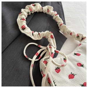 Detailed texture of white corduroy shoulder bag with vibrant red strawberry prints