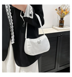 Close-up of white satin shoulder bag featuring a silver butterfly metal ornament detail