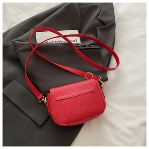 Detailed view of red saddle bag with litchi grain texture and gold metal hardware