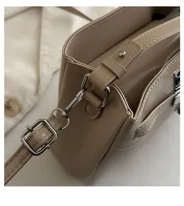 Detail of silver metal hook and pebble grain leather strap on beige bucket bag