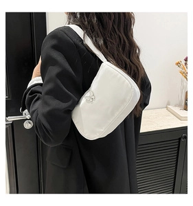 Detail of the white underarm bag with a silver butterfly metal buckle and fabric texture
