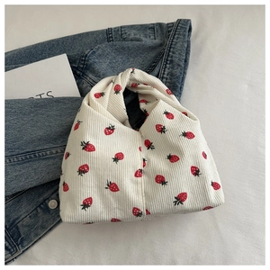 Gros plan du sac à main en velours côtelé fraise sur une veste en denim