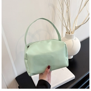 Detail of mint green PU leather handbag with integrated handle on a minimalist table