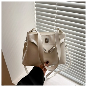 Close-up of cream leather handbag featuring silver twist lock and adjustable shoulder strap