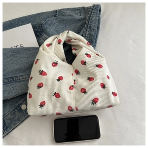 Détail du sac à main en velours blanc avec motif fraise rouge et poignée nouée chic