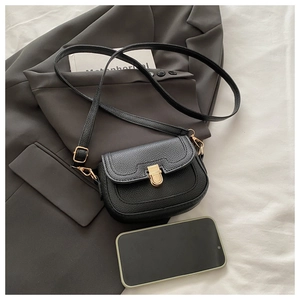 Close-up of black lychee leather crossbody bag with gold buckle and smartphone for scale