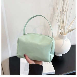 Close-up of mint green PU leather handbag with soft box structure and top handle grip