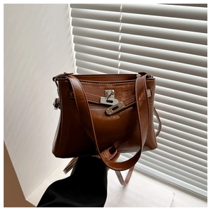 Macro shot of brown leather crossbody bag with metallic twist lock and strap details