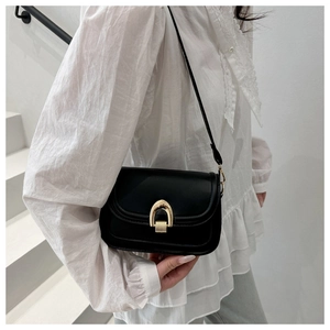 Detail of black crossbody bag featuring a horseshoe buckle and elegant gold-tone hardware