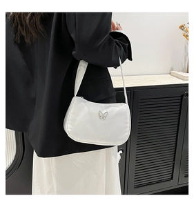 Detail of white nylon shoulder bag with silver butterfly buckle shown in shoulder-carry view