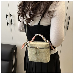 Rear view of a light green box bag with silk scarf handle worn by a model