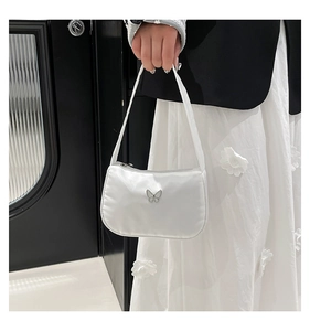 Detail of white nylon underarm bag featuring a silver butterfly metal ornament
