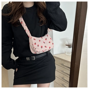 Close-up of pink corduroy crossbody bag with cute strawberry pattern on model
