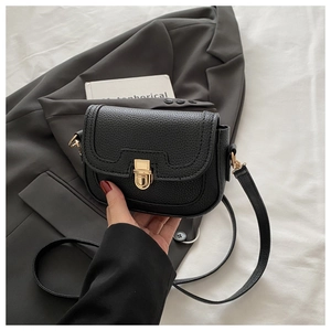 Close-up of black litchi grain leather shoulder bag with golden metallic lock and strap