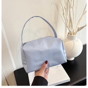 Detail of light blue candy-colored small square handbag with smooth texture and top handle