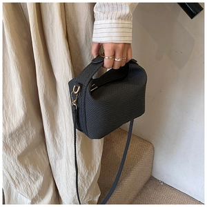 Detail shot of black waffle texture handbag with golden hardware and elegant handle