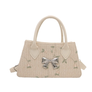 Beige woven handbag with floral embroidery and silver bow detail on white background