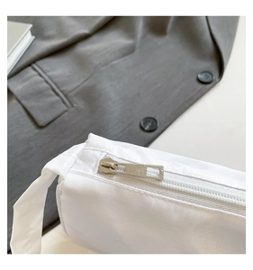 Detailed macro view of white fabric texture and silver metal zipper on a fashion bag