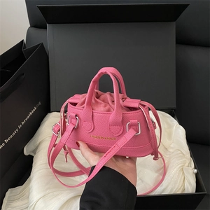 Detailed view of pink pebble leather shell bag in a luxury gift box with drawstring interior