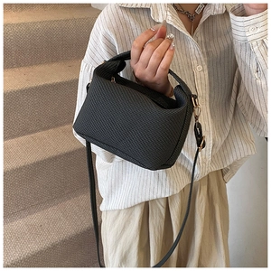 Close-up of black waffle textured mini crossbody bag shown on a model with gold hardware
