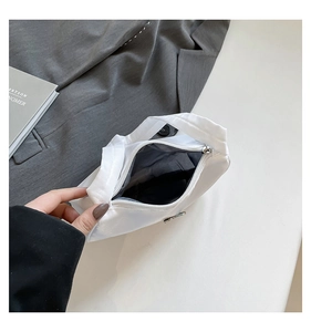Close-up of minimalist white fabric handbag showing zipper closure and grey interior lining