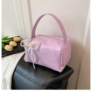 Detail of lavender handbag with pearl lace bow charm on black leather seat