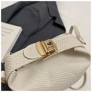 Detail of minimalist cream woven bag with golden rectangular buckle and sleek texture