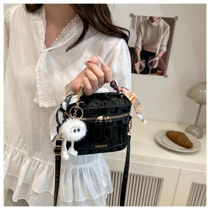 Detail of black velvet handbag with golden hardware, silk scarf handle, and eye charm