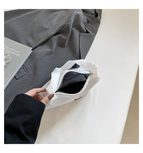 Detail of white nylon shoulder bag featuring a metallic triangle logo and zip closure