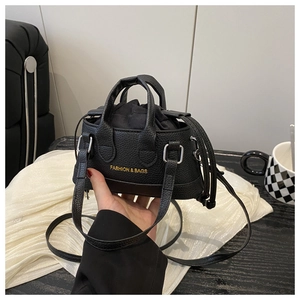 Close-up of black litchi grain leather mini bag with gold fashion text and drawstring inner