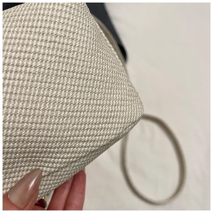 Close-up of beige woven texture and round strap detail on this stylish crossbody bag