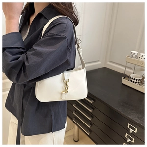 Close-up of a minimalist white leather baguette bag with a vintage gold piston buckle