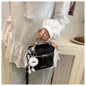 Detail of black textured crossbody box bag with silk scarf handle and plush charm