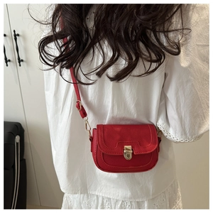 Detail view of red textured leather crossbody bag with golden metal clasp and adjustable strap
