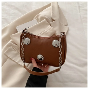 Detail of brown leather crescent bag with silver metallic buckles and chain strap