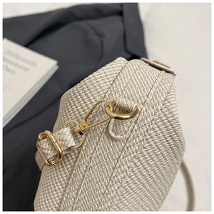 Detailed macro of golden metal lobster clasp and hooks on woven crossbody bag