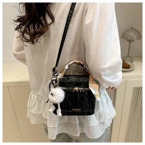Detail of black faux leather box bag with silk scarf handle and plush ball charm charm
