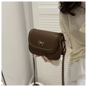 Detail of dark brown matte leather handbag with elegant gold bow metal buckle clasp