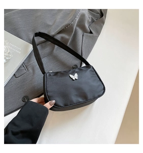 Close-up of a black nylon shoulder bag featuring a stylish white butterfly-shaped buckle