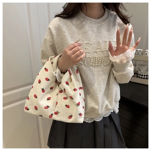 Détail du sac cabas en velours côtelé crème avec imprimé fraise porté par le mannequin