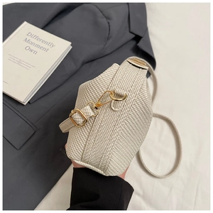 Detail of cream woven handbag with herringbone texture and gold metal hardware accents