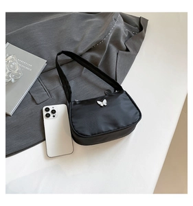 Detail of black nylon underarm bag with white 3D butterfly decoration and zipper