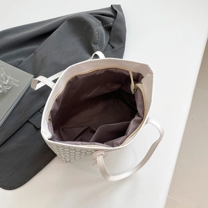 White quilted tote bag with black letter print and spacious interior shown from top view
