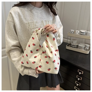 Détail de la texture d'un sac cabas en velours côtelé fraise tenu dans un cadre chaleureux