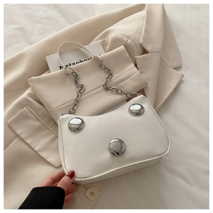 Detailed view of white crescent bag featuring large polished silver metal studs and chain