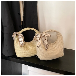 Vue détaillée du sac à main en paille tressée avec ruban en soie sur une surface sombre